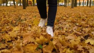 穿着运动鞋的女人脚在地上行走，地上长满了秋天的落叶